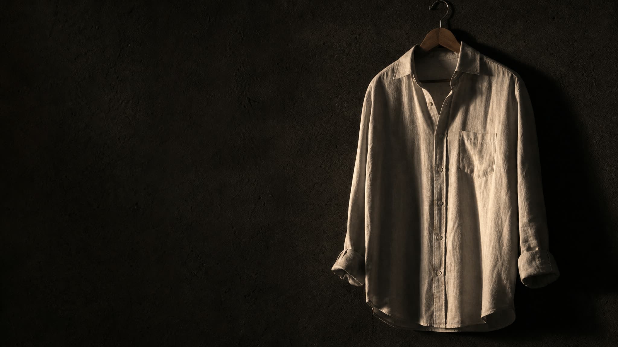 The same shirt on the same hanger at dusk, lit from the side so the drape and the creases show instead of the weave.